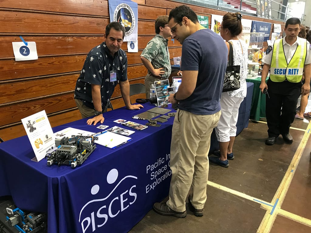 PISCES Director Rodrigo Romo talks with visitors about Hawaiʻi basalt research and ISRU. 