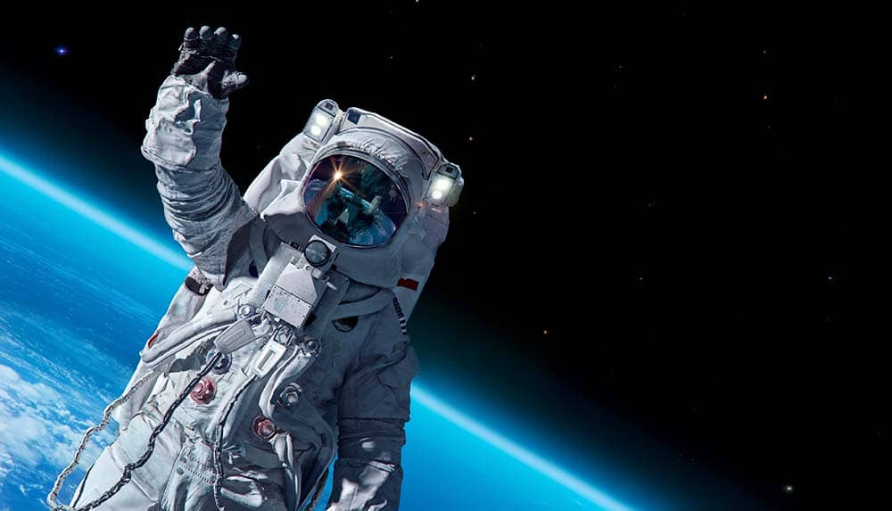 astronaut floating in space above Earth waving hello